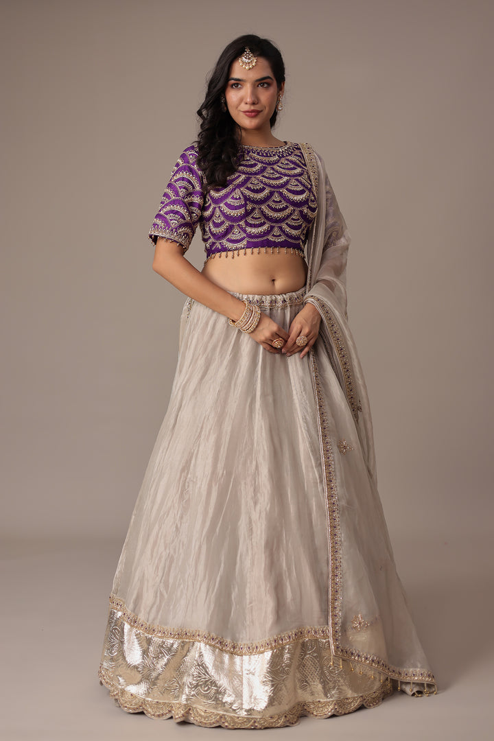 Ivory Shimmer Tissue Lehenga with Intricate Aari, Pearl, Thread & Zardozi Embroidery Paired with a Royal Purple Blouse