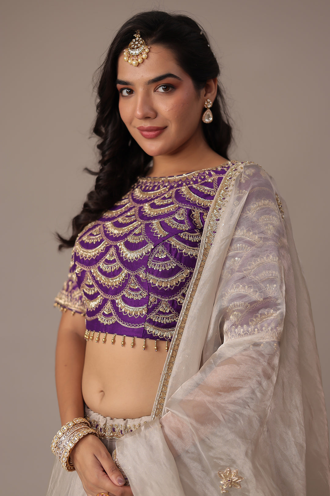 Ivory Shimmer Tissue Lehenga with Intricate Aari, Pearl, Thread & Zardozi Embroidery Paired with a Royal Purple Blouse