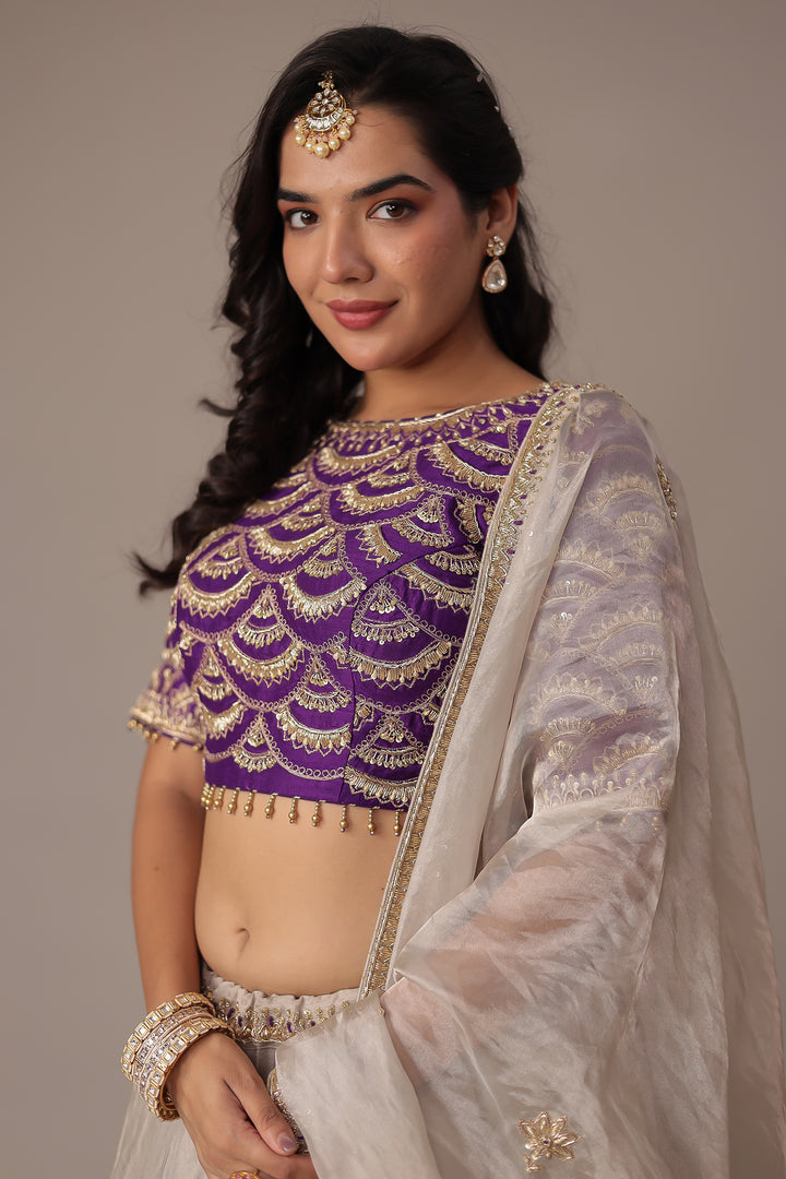 Ivory Shimmer Tissue Lehenga with Intricate Aari, Pearl, Thread & Zardozi Embroidery Paired with a Royal Purple Blouse