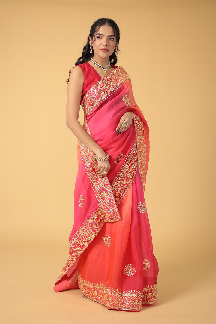 Woman wearing a pink saree with gold embroidery on a beige background